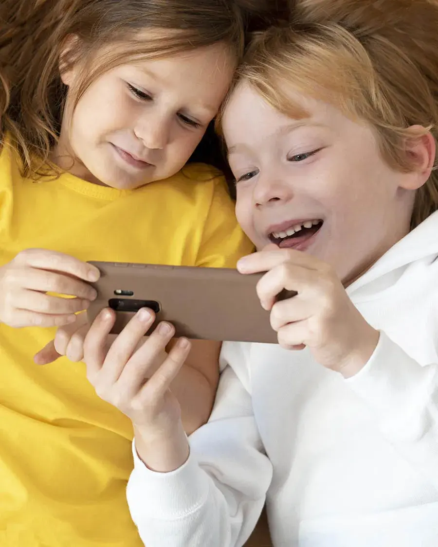 vista-superior-de-criancas-sorridentes-usando-smartphone-juntos